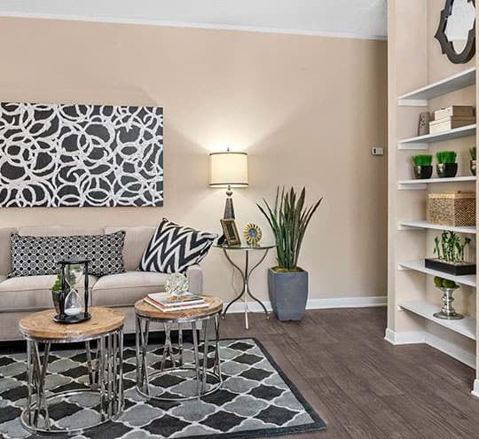 a living room with a white couch and black and white flooring at The  Woodlands Apartments