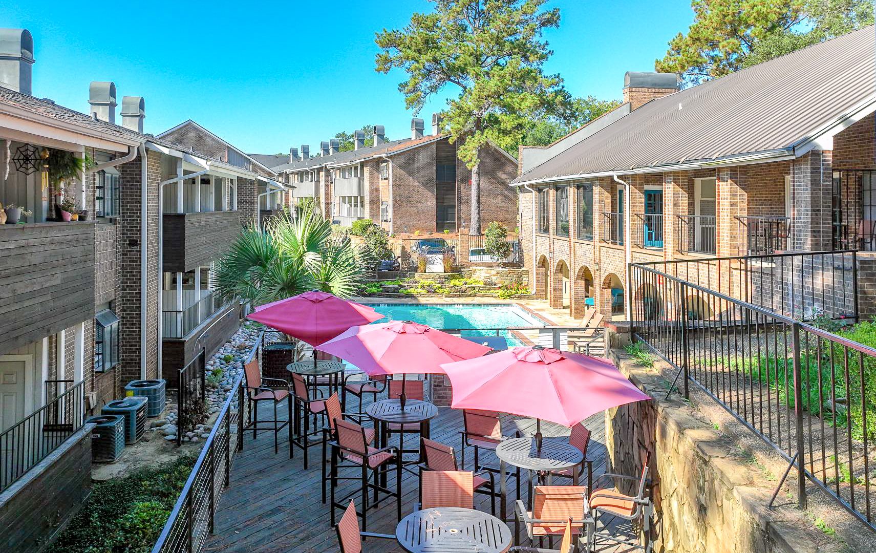 a patio area with tables, chairs and umbrellas